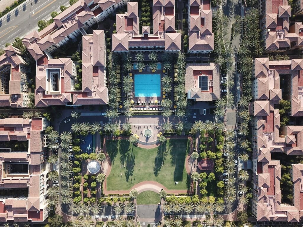 Explore an aerial view of a luxurious residential complex featuring a central swimming pool and lush gardens in Irvine, CA.