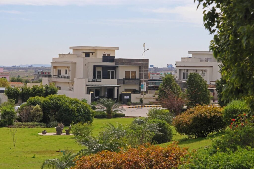 A scenic view of a modern multi-story luxury house overlooking a lush green park in Top City-1 Islamabad.