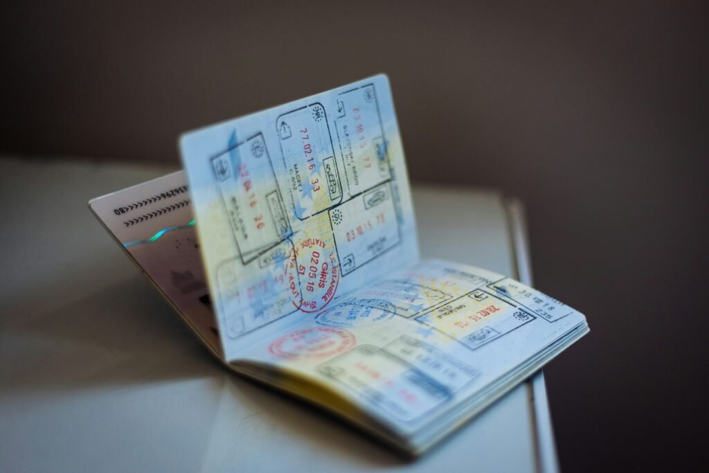 An open passport booklet filled with various colorful international entry and exit immigration stamps.
